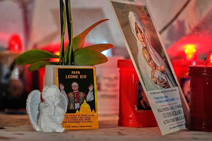 An image of Pope Leo XIV rests at the base of a statue of the late Pope John Paul II outside the Agostino Gemelli Polyclinic, Rome, Oct. 13, 2026